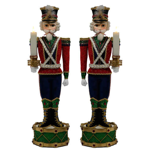 Two decorative nutcracker figurines holding candles on a white background
