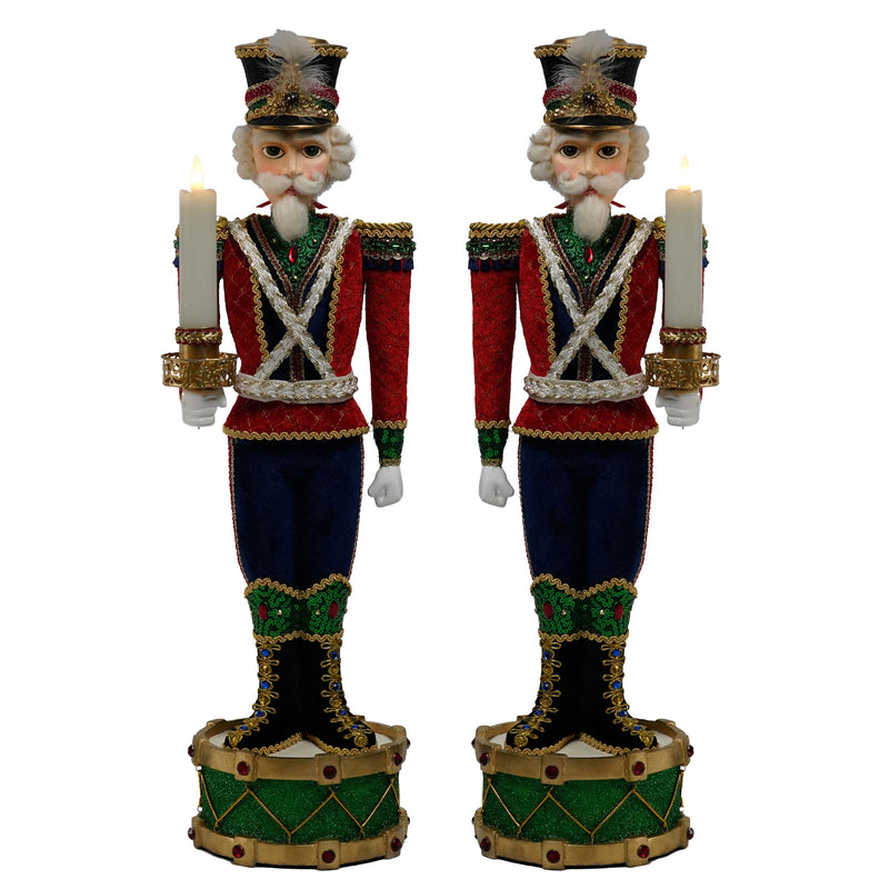 Two decorative nutcracker figurines holding candles on a white background